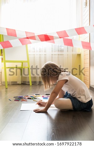 Quarantine, coronavirus covid-19. Red warning tape. Little girls draw with semi-colored pencils and felt-tip pens on paper sheets on floor in bedroom. Self-isolation at home. Activity games with kids.