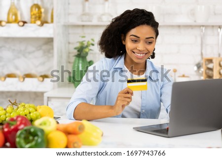 Stay At Home Concept. Happy african woman with laptop and credit card ordering food delivery online, copyspace