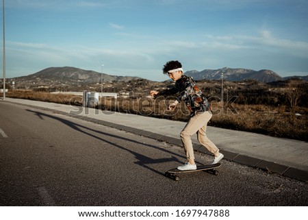Portrait Guy with style and modern with a longboard in the street. Young lifestyle