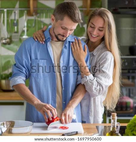 Enjoying cooking together. Happy young couple on the kitchen making delicious vegetarian healthy food