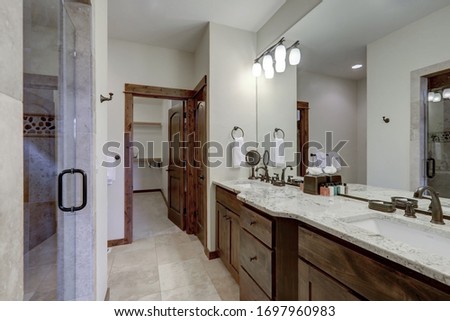Classic luxury but simple small bathroom interior with natural stone and rich dark wood and grey walls.