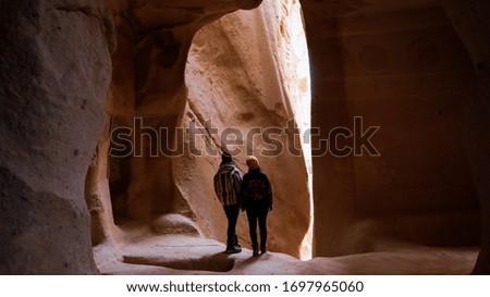 Travel couple standing into the cave surrounded by rock formations at Zelve Valley in Cappadocia, Turkey