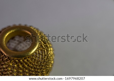 Round ball of golden wire macro photo. Women's lacy decoration. Decorative round openwork golden button close-up. Openwork festive golden vase. Gray background. 