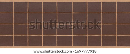 Relief pattern of painted dark brown squares on a light brown house wall - panorama in close-up
