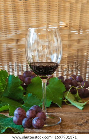 Glass of red wine and grapes on old wooden background. Vertical picture