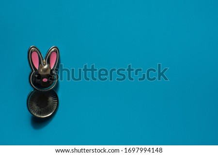 Pretty silver bunny on the vivid blue background as holiday greeting card. Place for Easter congratulations. Romantic banner. Copy space.