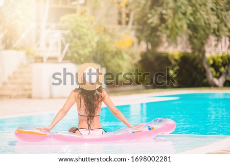 Beautiful young woman relaxing in swimming pool. Girl in bikini in outdoor pool at luxury hotel