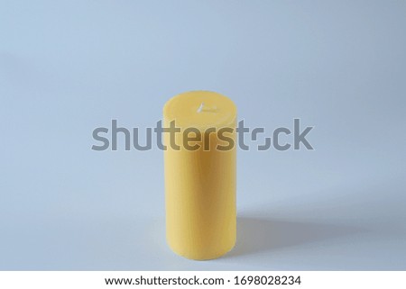 Tall yellow wax candle on white, close up view.