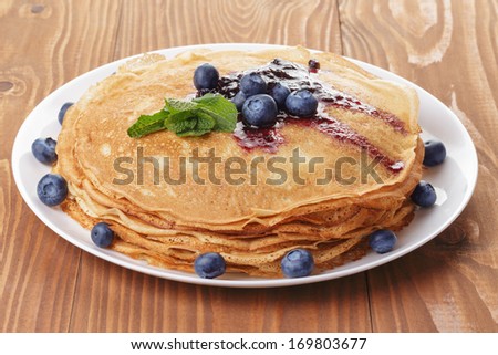 homemade blinis or crepes with blueberries and jam, on wooden table Royalty-Free Stock Photo #169803677