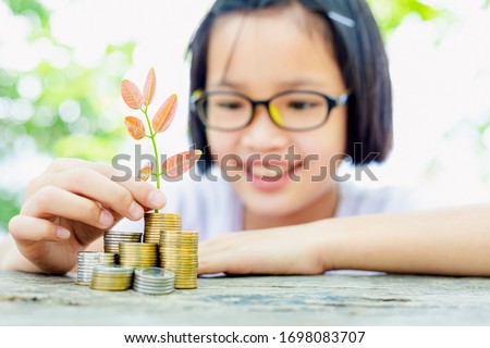 Child putting plant on coin stack growing graph with nature background,investment concept.Business Finance and Save Money concept