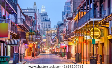 Bourbon St, New Orleans, Louisiana, USA cityscape of bars and restaurants at twilight.