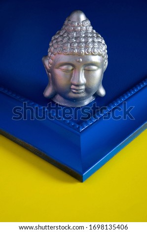 Silver Gautama Buddha Head on Colorful Blue and Yellow Background Vertical