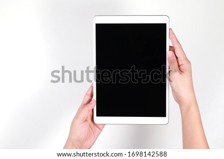 Hands holding a blank screen tablet computer over light background