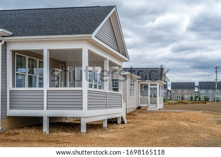 Newly built American single family home in a 55+adult residential community with a covered porch partially enclosed with gray horizontal vinyl siding in Maryland Royalty-Free Stock Photo #1698165118