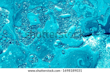 Turquoise watercolor ink in water with oil. Futuristic trend background. Planets, the universe and space. Cool trending screensaver. Abstract background.