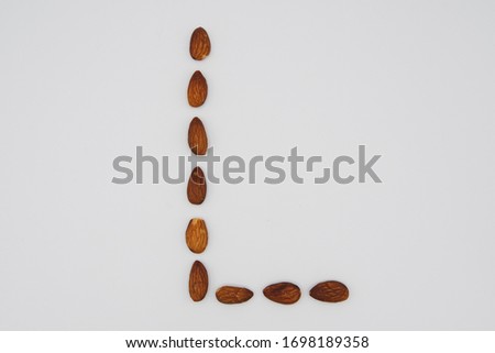 Letter L in uppercase made with almond nuts on a clean white background, capital letter lowercase Royalty-Free Stock Photo #1698189358