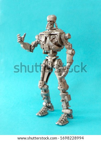 Figurine and statue of a robot made of metal. Cyborg robot close-up on a blue background. Robot toy.