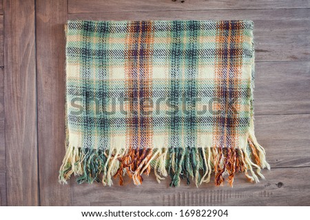 A folded tartan scarf on a wooden background