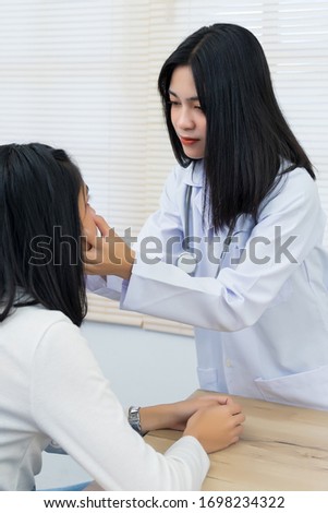 Young Asian female doctor checks adult woman patient to examine and diagnose her sickness and symptom. Medicine and health care concept. Doctor and patient.