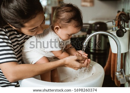 mother help her baby to wash hand in the sink Royalty-Free Stock Photo #1698260374