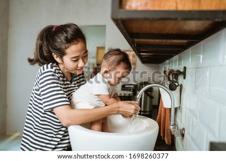 mother help her baby to wash hand in the sink Royalty-Free Stock Photo #1698260377