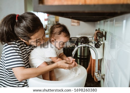 mother help her baby to wash hand in the sink Royalty-Free Stock Photo #1698260380