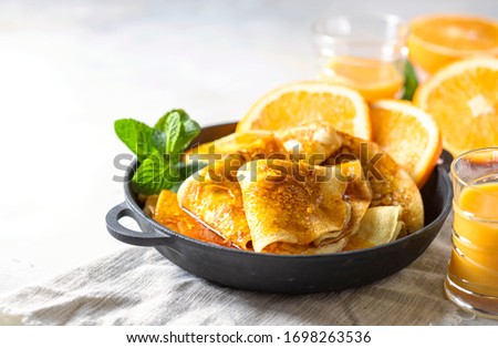 Crepes with Orange Sauce in a cast iron pan. Traditional French crepe Suzette with orange sauce. Selective focus, top view Royalty-Free Stock Photo #1698263536