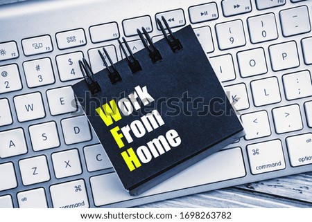 WORK FROM HOME text with keyboard and notepad on wooden background. Business and healthcare concept
