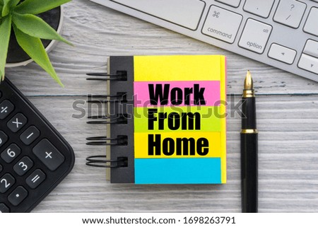 WORK FROM HOME text with decorative flower, calculator, fountain pen, keyboard and notepad on wooden background. Business and healthcare concept