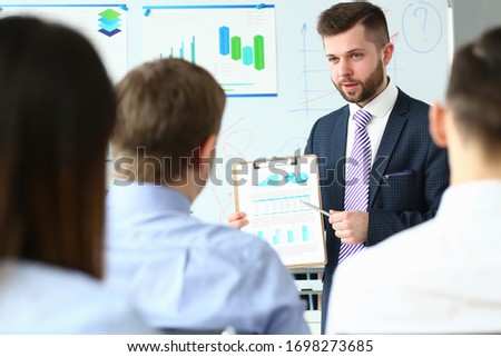 Handsome bearded man in suit and tie showing students document clipped to pad portrait