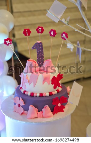 A wet birthday cake. Nigar inscription with candles . A purple inscription. White, purple, pink cake