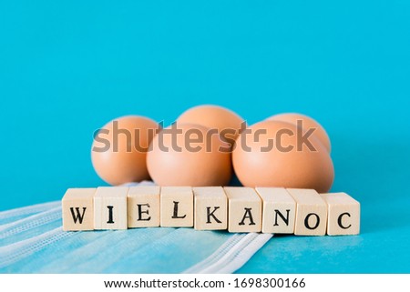 Eggs lying on face masks, wooden letters, "wielkanoc" means easter in polish
