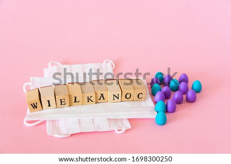 Plastic eggs lying on face protection masks, "wielkanoc" means easter in polish