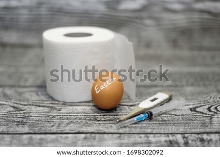 Easter egg, toilet paper, thermometer and syringe on the wooden background. Coronavirus Covid-19. Concept photo. Easter 2020.