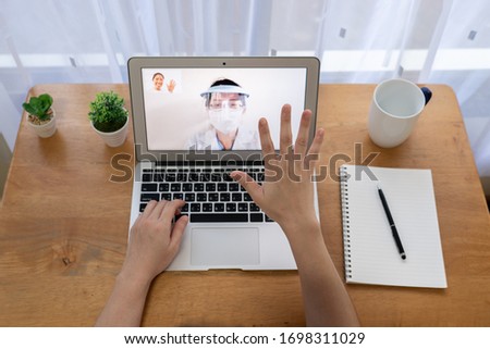 young asian woman staying at home uses vdo call to talk with her family who is doctor working at the hospital. covid-19, coronavirus, social distancing, isolation, quarantine, work from home concept Royalty-Free Stock Photo #1698311029