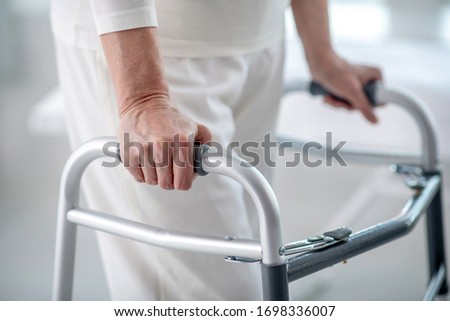 Walking disability. Close up of a female hand holding on to the walker while trying to walk Royalty-Free Stock Photo #1698336007