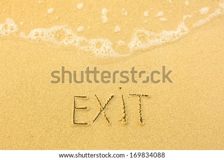 Exit - written in sand on beach texture - soft wave of the sea.