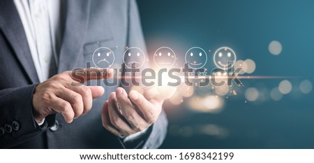 Customer evaluation feedback concept.men show him satisfaction on virtual interface screen  smartphone with a smiley face and five star rating.Service rating, satisfaction concept.