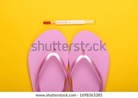 Flat lay summer background. Beach vacation. Flip flops and thermometer on a yellow background. Top view