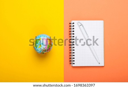 Globe and notebook on yellow orange background. Top view. Minimalism. Education concept, geography