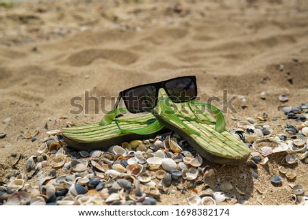 Accessories for the beach lying on the sand, men's slippers and sunglasses on the beach sand
