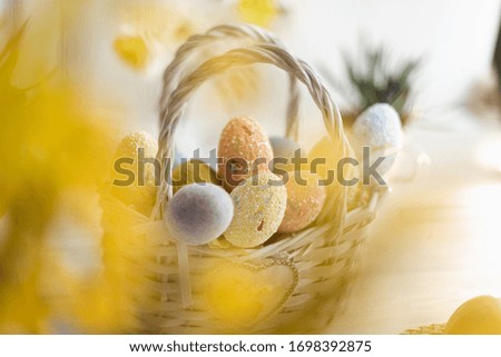 Multi-colored Easter eggs in a basket on a white wooden background.