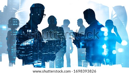 Silhouettes of diverse business people working together in abstract city with double exposure of blurry cityscape. Concept of teamwork, communication and corporate life. Toned image