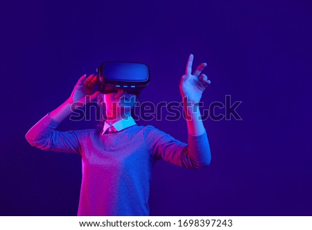 Girl in glasses of vertual reality on a colored background. Blue and purple colors. Royalty-Free Stock Photo #1698397243