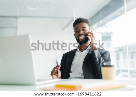 cheerful african american businessman talking on phone in the office