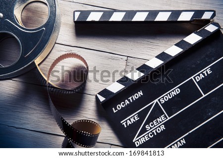 Movie clapper and film reel on a wooden background Royalty-Free Stock Photo #169841813