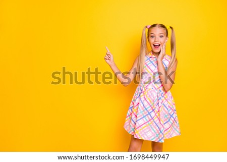 Photo of funny beautiful small lady good mood pretty long tails direct finger empty space show sale prices wear checkered plaid summer dress isolated yellow bright color background