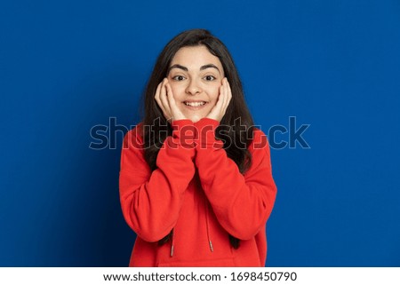 Brunette young girl wearing red jersey on a blue background