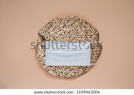 Round matzah in medical mask. Pesach celebration concept during the CoVid19 epidemic and quarantine.