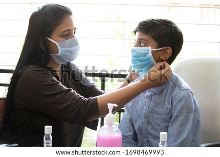 Mother helping son how to wear a face mask and stay safe from infectious coronavirus disease Royalty-Free Stock Photo #1698469993